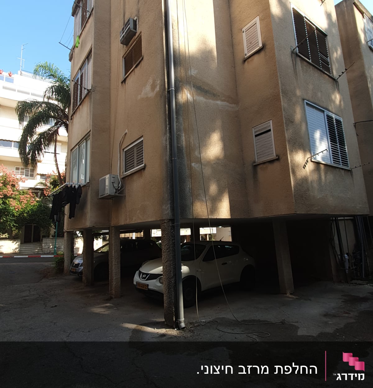 בניין עם חבלי כביסה, מכוניות חונות, ציוד על הקרקע